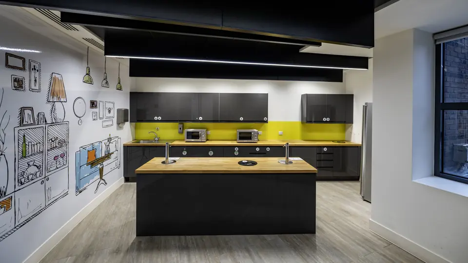 Office kitchen with island, yellow splashback and illustrated feature wall